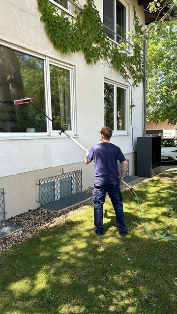 Mitarbeiter mit Teleskopstange an einem Wohnhaus